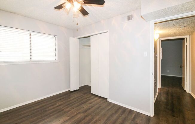 an empty living room with white walls and a ceiling fan