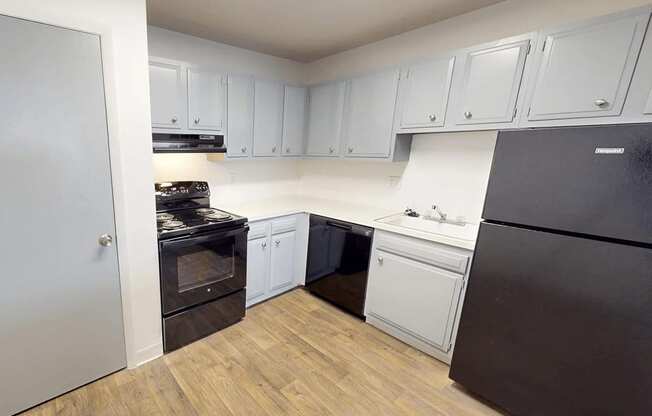A kitchen with black appliances and white cabinets.