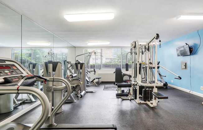 A gym with a variety of equipment including treadmills, weights, and exercise machines.
