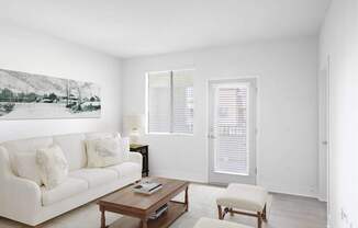 A living room with a white couch, a coffee table, and a painting on the wall.