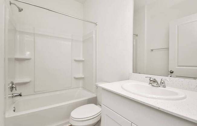A white bathroom with a toilet, sink, and bathtub.