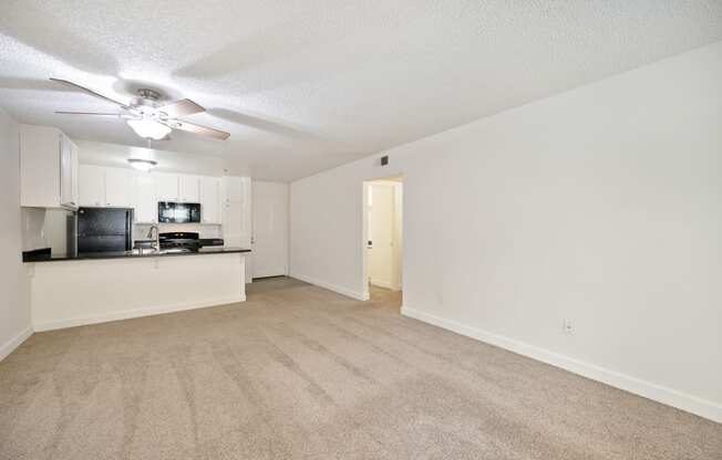 an empty living room and kitchen with a ceiling fan
