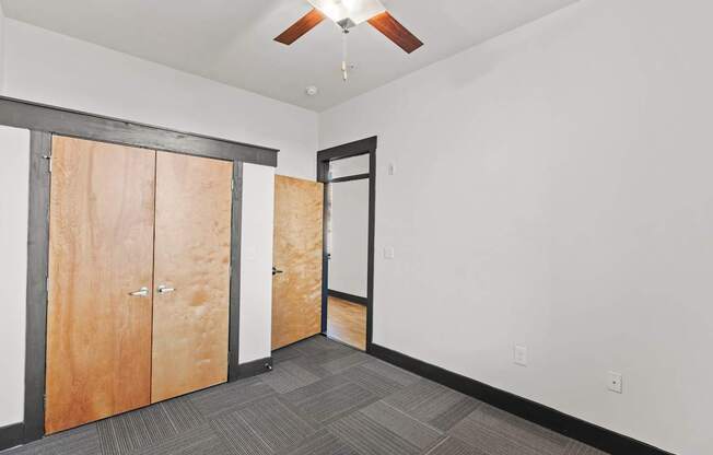 A room with a ceiling fan and a row of wooden doors.