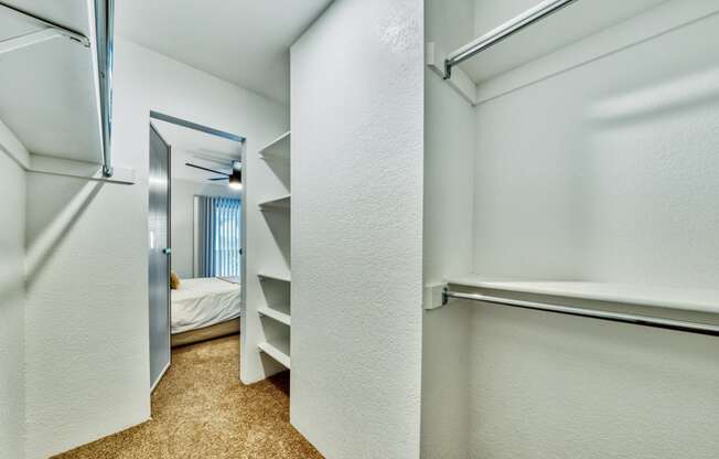 a walk in closet with shelves and a mirror in a room with a bed