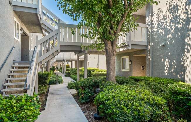 a sidewalk in front of an apartment building with stairs