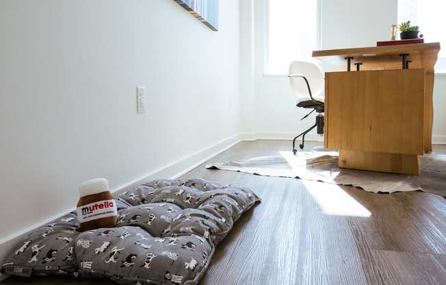 bedroom in b1 floorplan staged as office with pet bed on the floor at Sky on Main Apartments in Kansas City