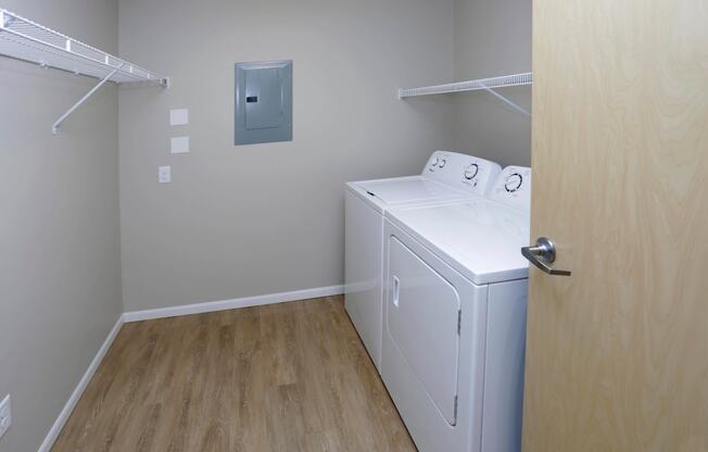 In unit washer and dryer located in the walk-in closet with storage shelves and hanging space.