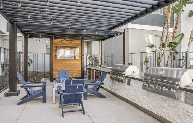 an outdoor patio with blue chairs and a grill and a tv