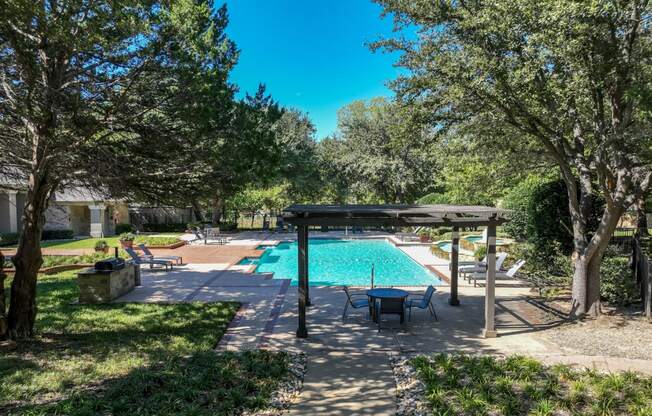 a resort-inspired swimming pool surrounded by lush landscaping at Stoneleigh on Spring Creek apartments