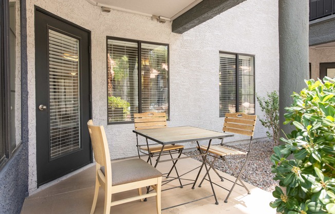 a patio with a table and chairs outside of a house