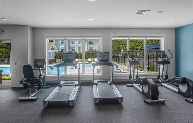 a gym with cardio equipment and a window view of a pool