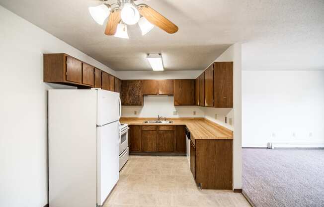 Bismarck, ND Rosser Apartments. a kitchen with a white refrigerator freezer next to a stove top oven