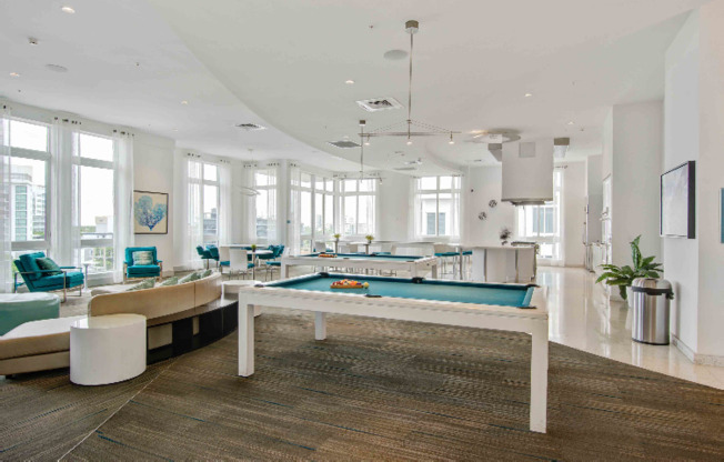 Large resident lounge with blue seating and pool tables inside SOMA at Brickell apartments.