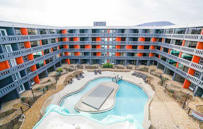 A large building with orange and grey balconies overlooks a pool.