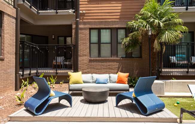 a patio with blue chairs and a couch and a fire pit