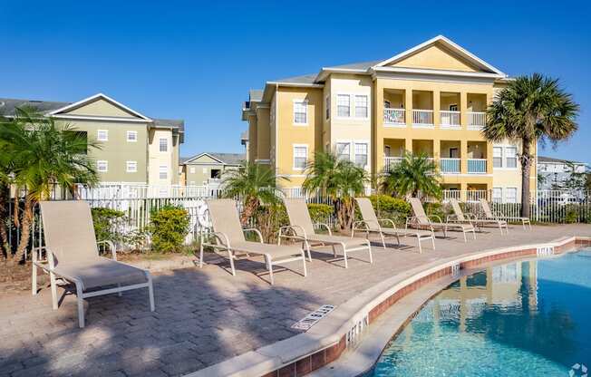 A pool area with chairs and a building in the background.
