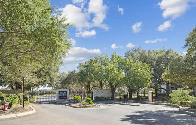 the entrance to a park with trees and a street