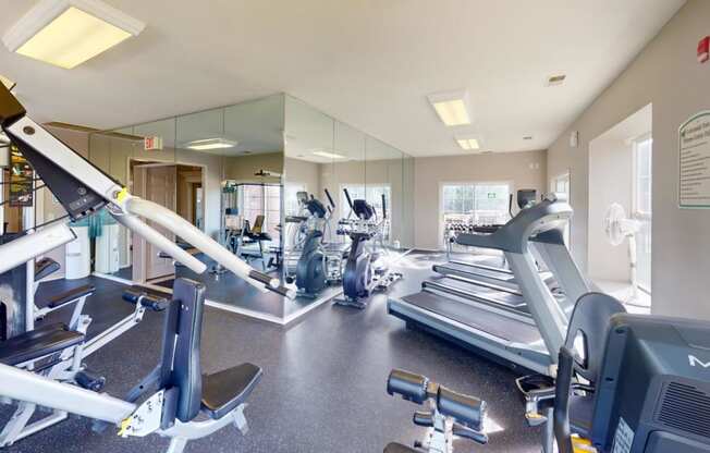 a gym with cardio equipment and mirrors in a building