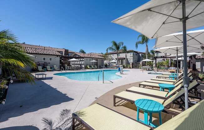 a swimming pool with lounge chairs and umbrellas in a resort style pool area