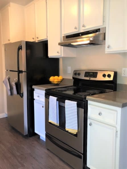 Galley style kitchen with white upper and lower cabinets, and full sized appliances
