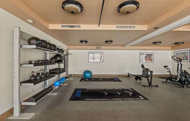 A gym with a variety of equipment including weights, a balance ball, and a stationary bike.