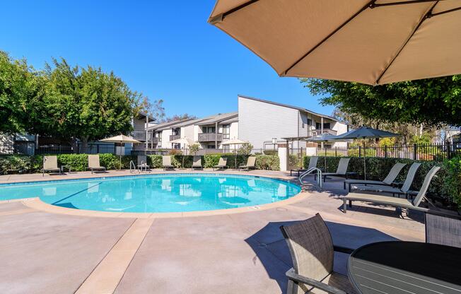 A swimming pool surrounded by lounge chairs and umbrellas.