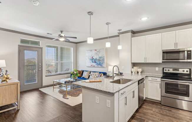 a kitchen with an island and a living room with a door to a balcony