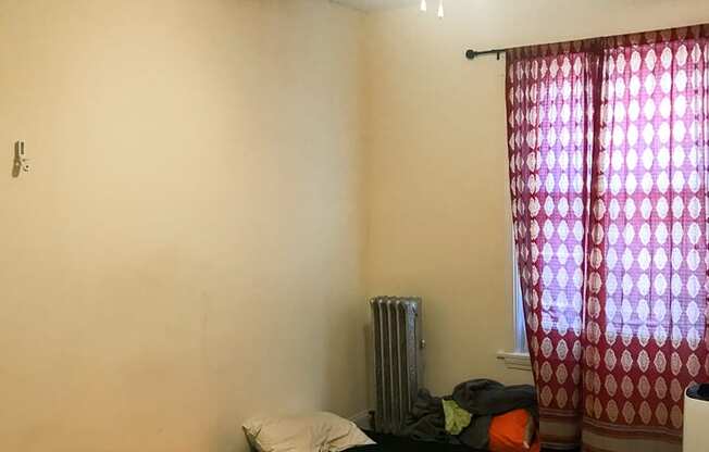 A bedroom with a bed, a ceiling fan, and a window with curtains.