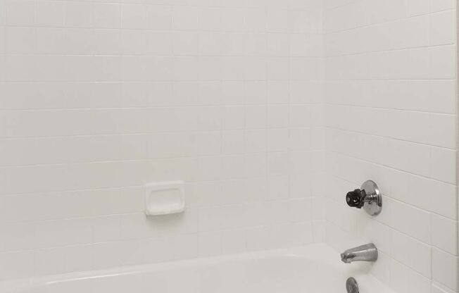 A white bathtub with a shower head and faucet.