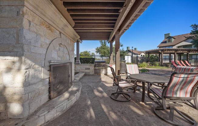 a covered patio with chairs and a table and a fireplace at The Fairways at Star Ranch, Hutto