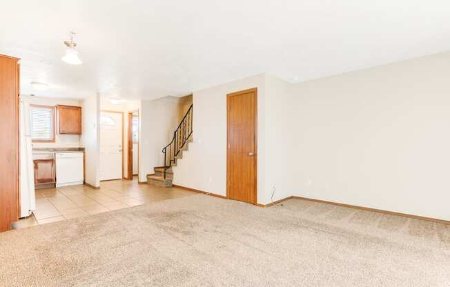 a living room with a beige rug and a kitchen in the background