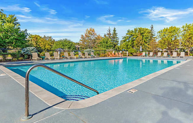our resort style swimming pool is surrounded by lounge chairs and trees