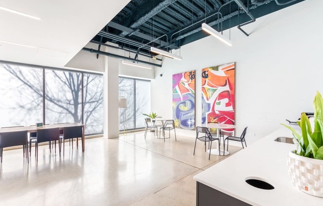 a large room with tables and chairs and paintings on the wall