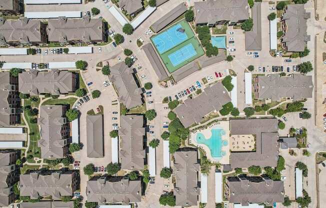 A bird's eye view of a residential area with houses, cars, and a swimming pool.