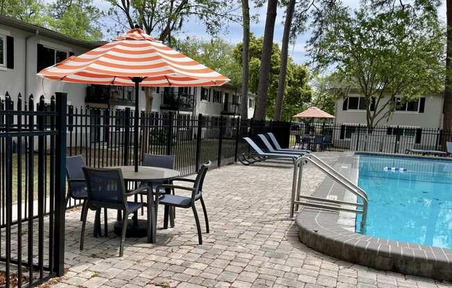 a swimming pool with a table with an umbrella and chairs