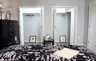 A bedroom with a black and white bedspread and a black dresser.
