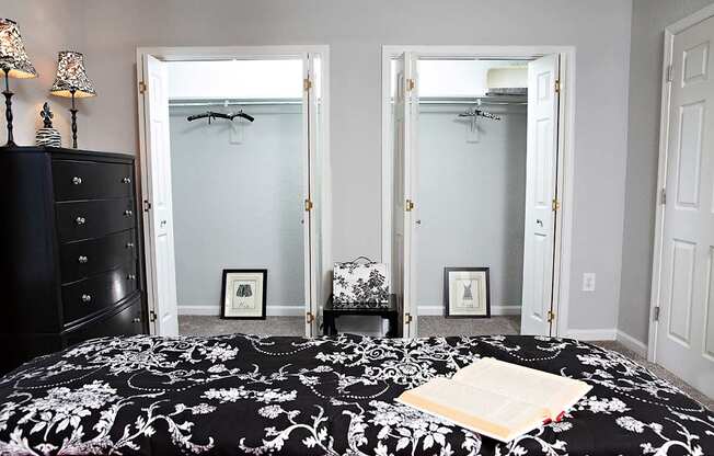 A bedroom with a black and white bedspread and a black dresser.