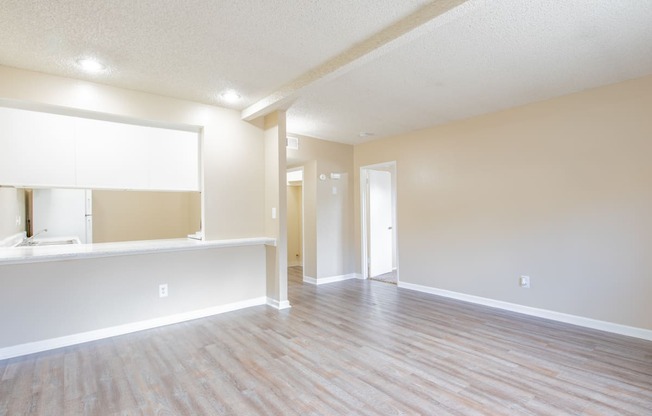 an empty living room and kitchen with a wood floor