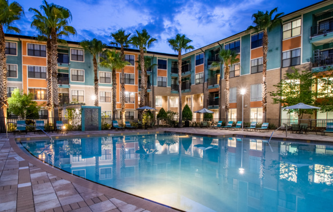 Beautiful swimming pool surrounded by lounge chairs and umbrellas at Orlando apartment community
