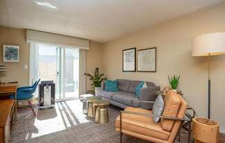 A living room with a grey couch, a blue chair, a wooden table, and a lamp.