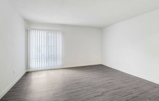 an empty living room with a window and wood floors