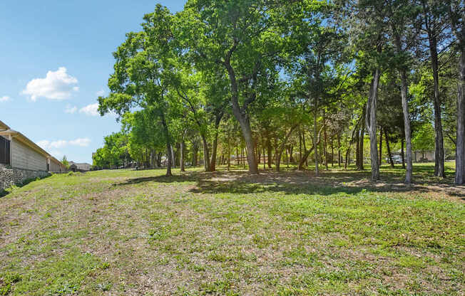 A field with trees and a house in the background.