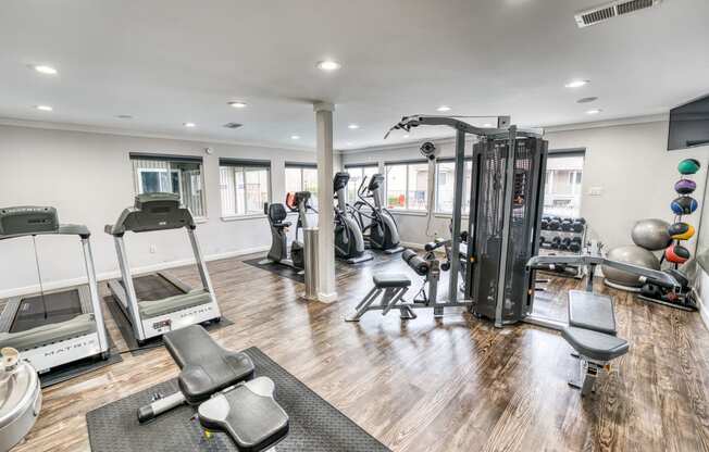 a gym with cardio equipment and weights on a wooden floor