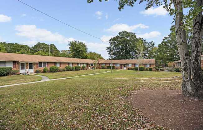 A grassy area in front of a building with a tree on the right.