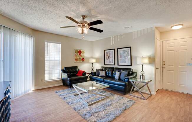 a living room with leather furniture and a ceiling fan