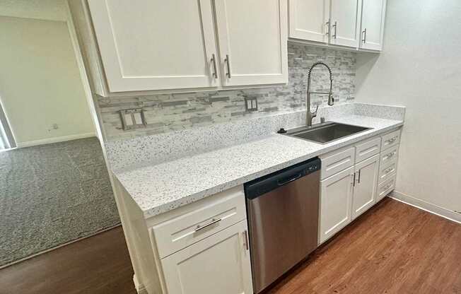 a kitchen with white cabinets and a stainless-steel dishwasher  at Willow Tree Apartments, California, 90505