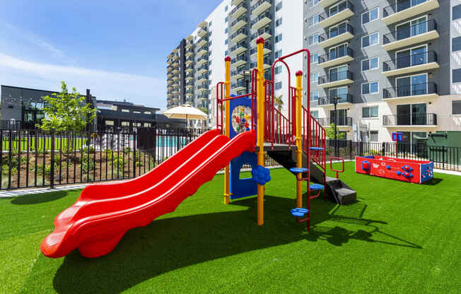 a playground at an apartment building with a red slide