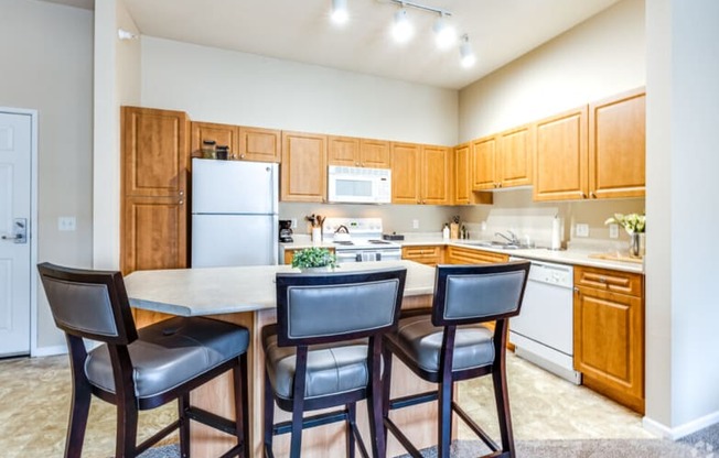 a kitchen with wooden cabinets and a counter top with three chairs