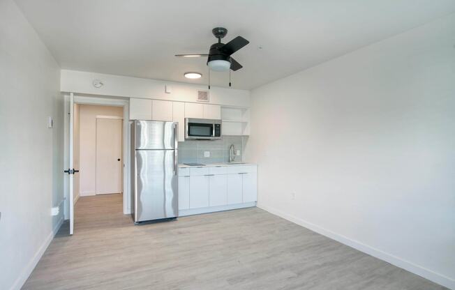 a renovated kitchen with white cabinets and a stainless steel refrigerator at Presidio Palms Apartments, Arizona , 85701