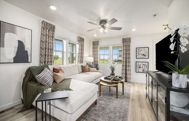 a living room with a white couch and a ceiling fan